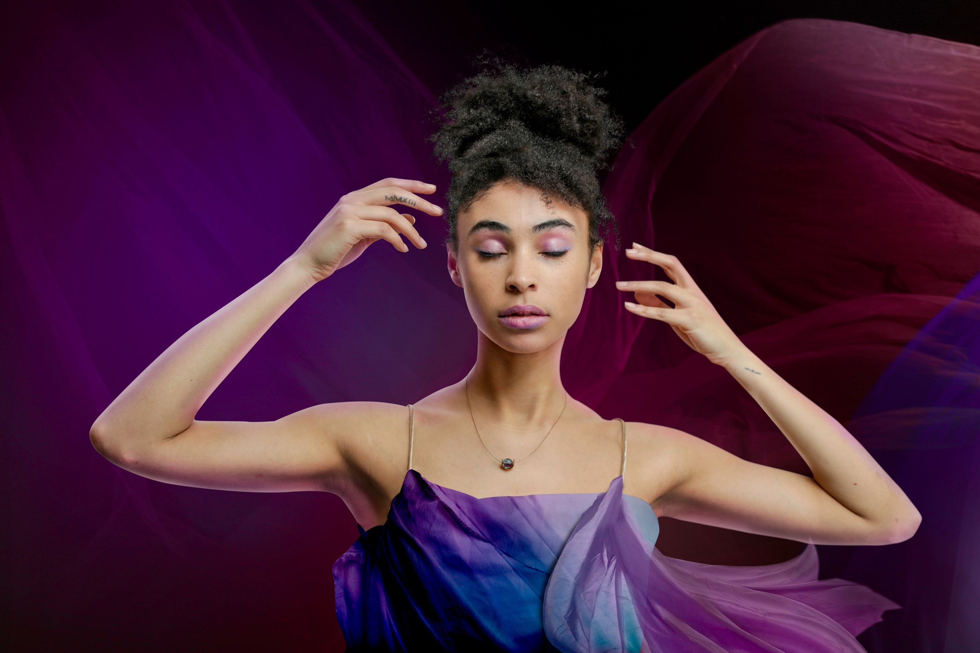 Woman with colorful fabric behind her